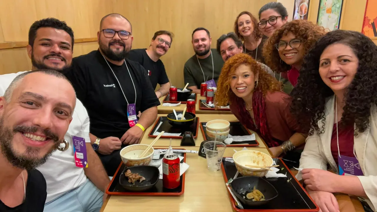 mesa comprida de refeitório com o grupo almoçando junto, bandejas à frente
